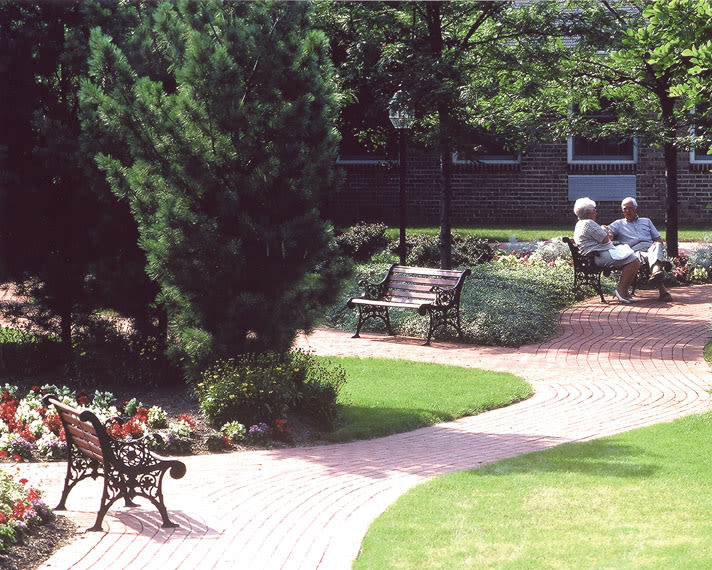 Elderly couple sitting on bench in garden courtyard