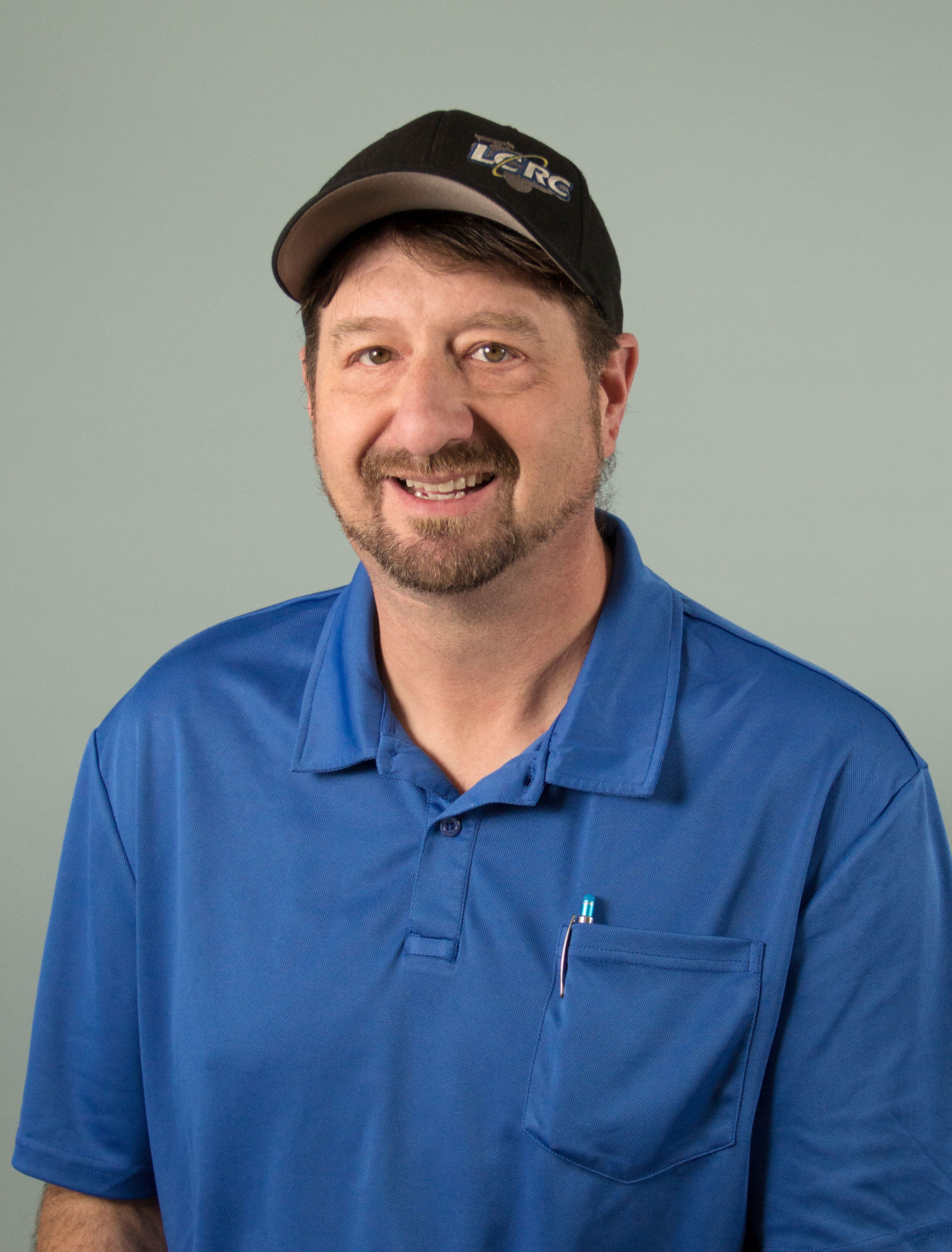 Smiling man in blue polo and black cap