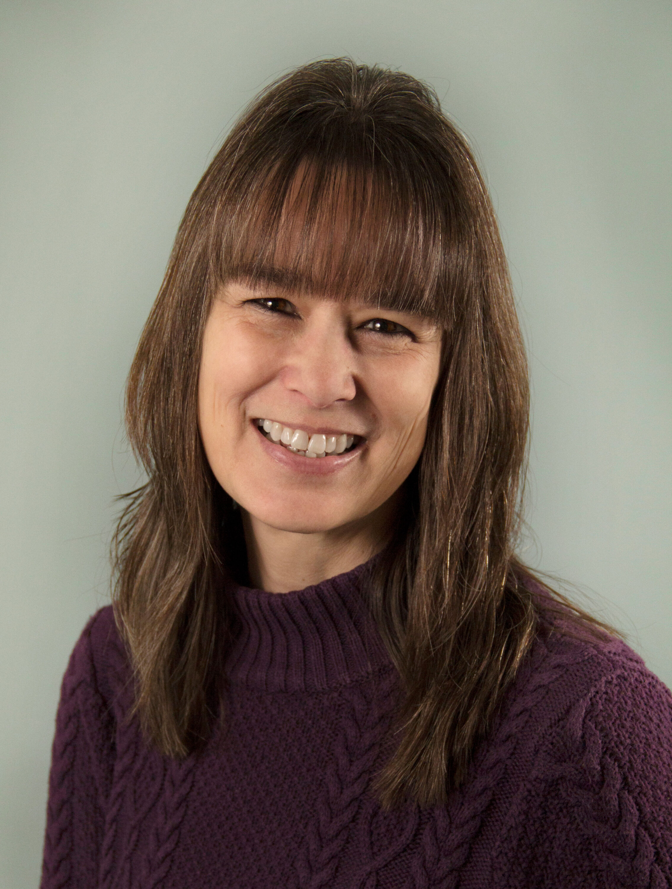 Smiling woman with brown hair in purple sweater