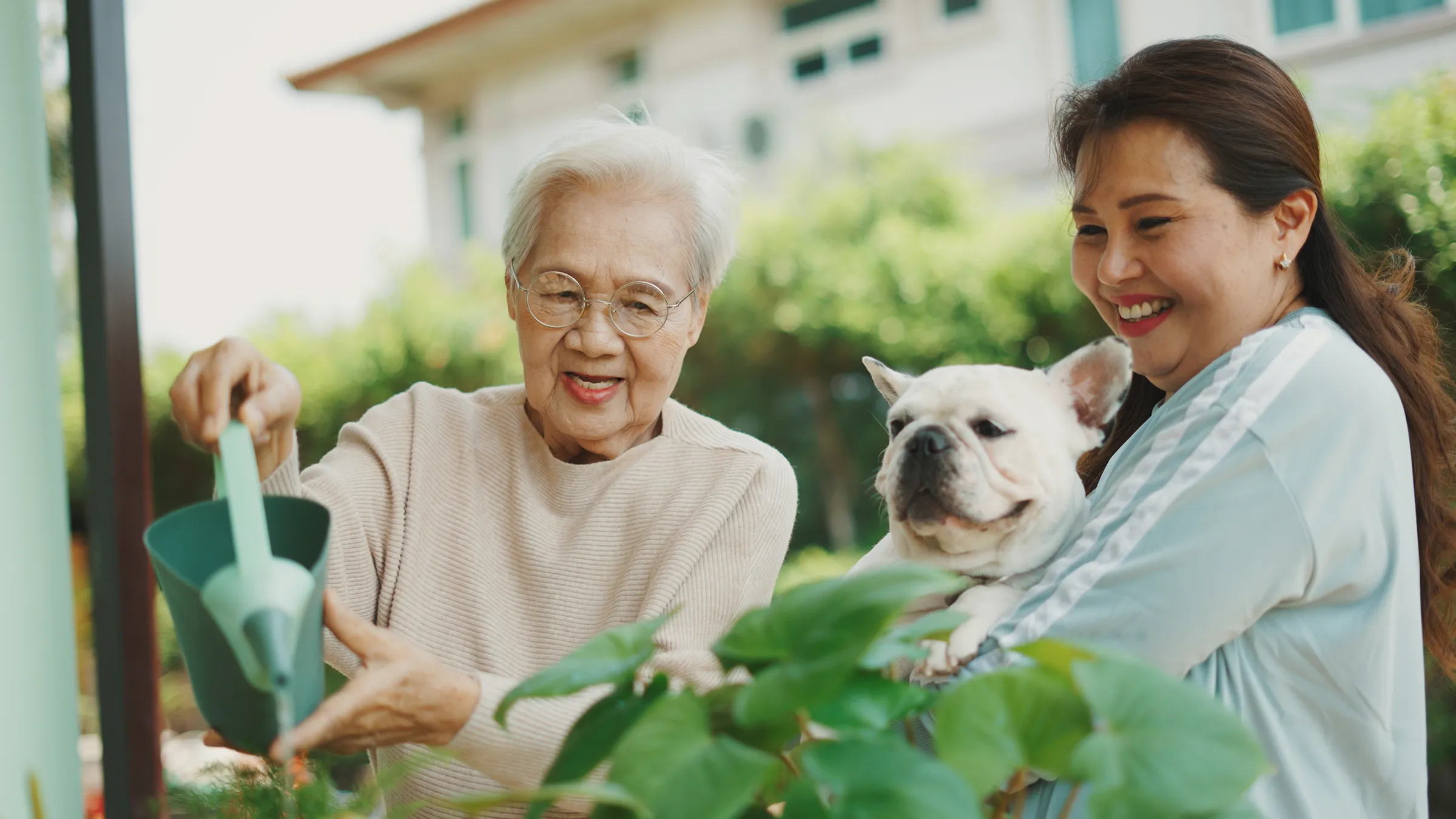 Elderly woman watering plants with daughter and dog